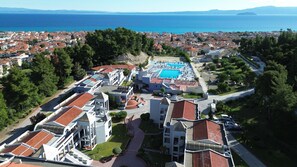 Um resort costeiro com piscina, edifícios em terraços e vista para o mar.