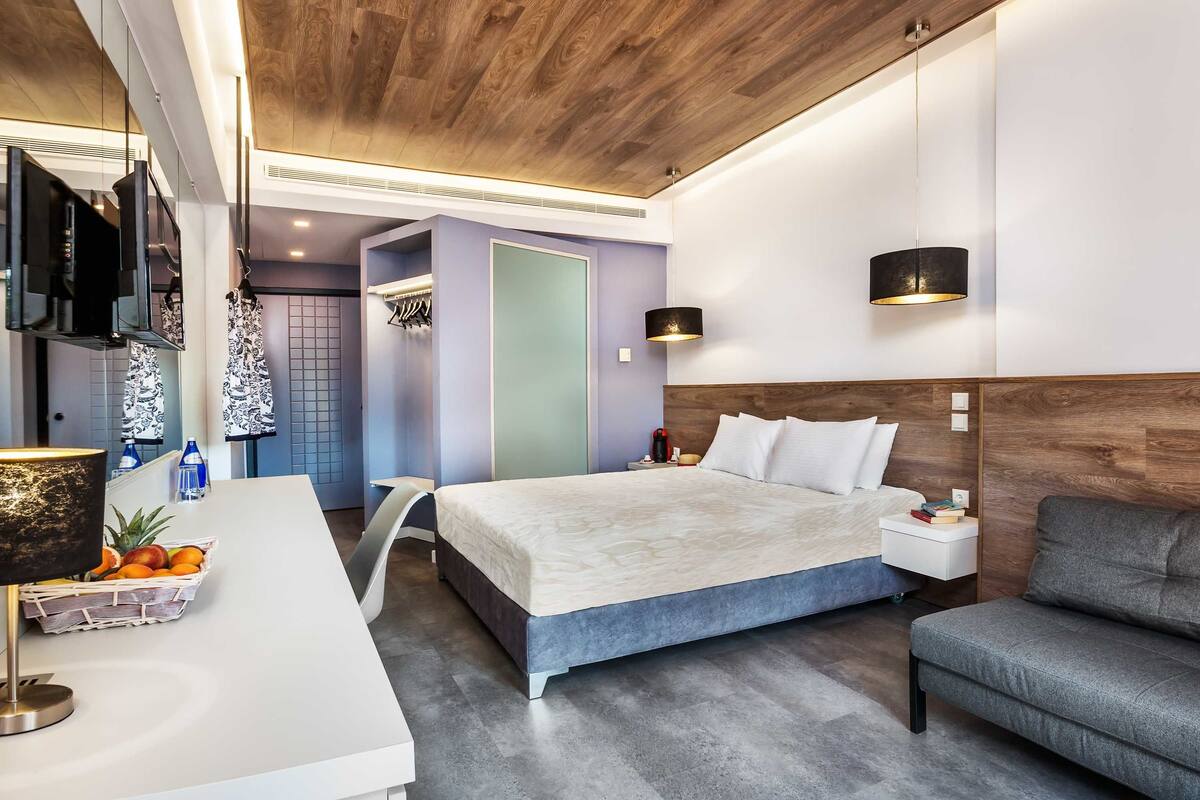 Una habitación de hotel moderna con una cama grande, un escritorio con lámpara, una silla y un televisor.
