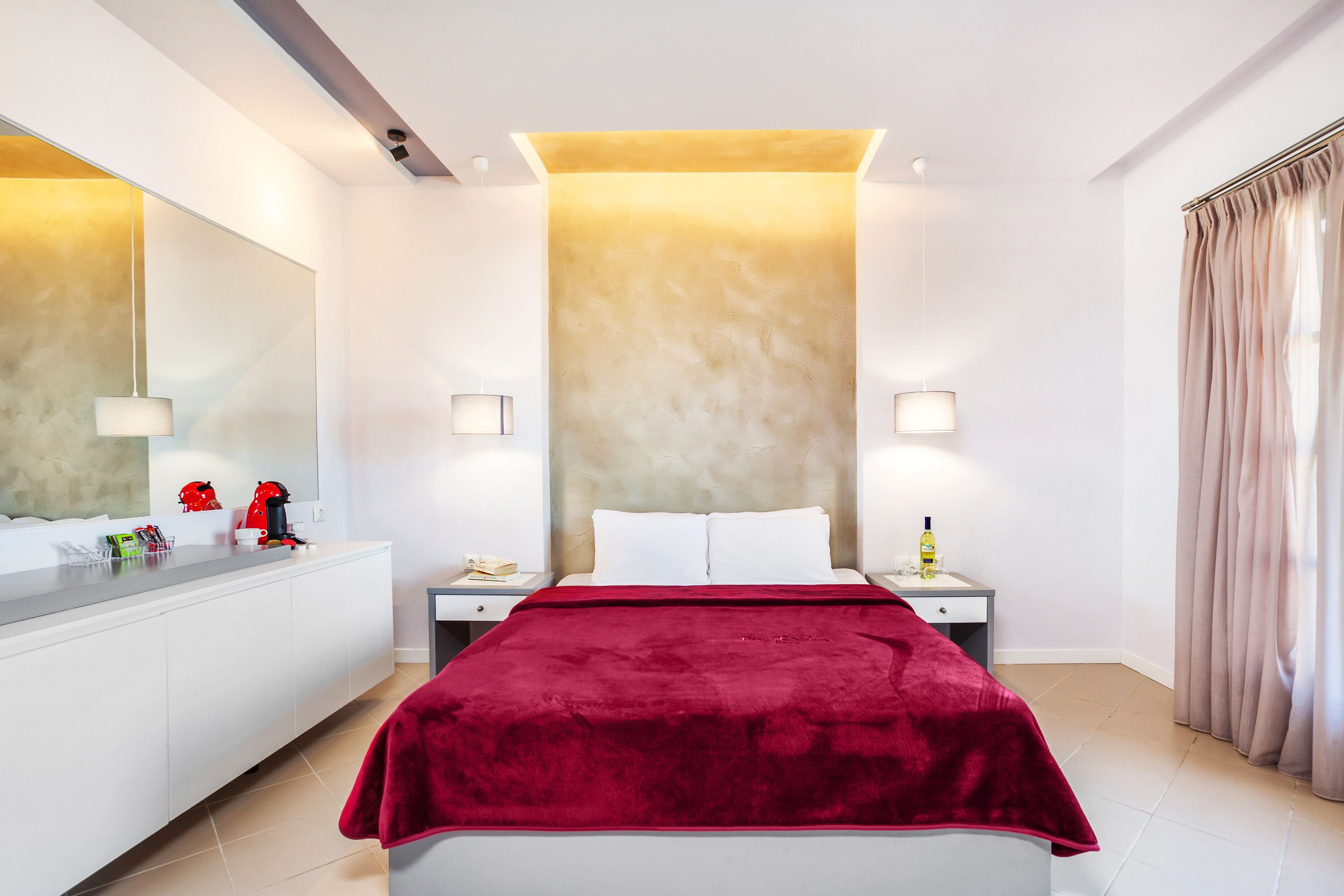 A modern hotel room with a large bed, a white vanity, a mirror, and a red throw blanket.