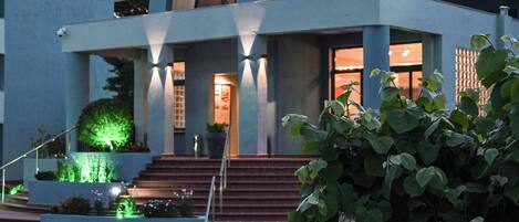 A modern building with a dome structure, steps leading to the entrance, and a well-lit facade.