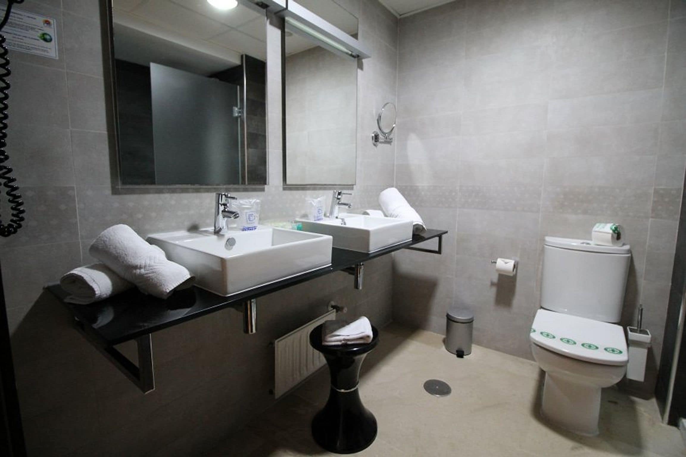 Un baño moderno con dos lavabos, un inodoro y un espejo.
