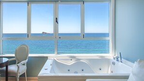 A room with a large window offering a view of the sea, a bathtub, and a chair. - Villa del Mar Hotel (Benidorm)