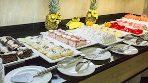 A buffet with various desserts and tropical fruits.