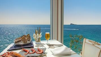 Uma mesa com frutos do mar, um copo de vinho e vista para o mar.