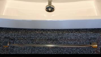 Un bany amb un lavabo blanc, dues copes de vidre i productes de tocador a la superfície.