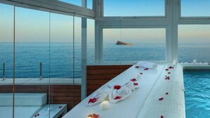 Un espace aménagé au bord de la piscine, avec vue sur la mer, une terrasse en bois et un fauteuil de relaxation.