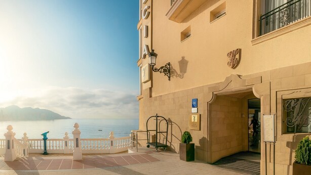 L’entrée d’un hôtel donnant sur la mer, un chemin d’accès fermé par un portail et un panneau indicateur.