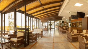 A spacious lobby with wicker furniture, a bar area, and large windows allowing natural light. - Magic Tropical Splash (Finestrat)