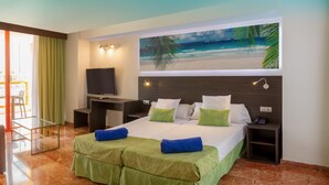 A hotel room with a bed, a TV, a desk, and a balcony with a table and chairs. - Magic Tropical Splash (Finestrat)