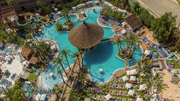 Una piscina al aire libre, sombrillas, sillones reclinables de piscina