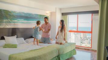 Una habitación de hotel con una cama, un ventanal con vistas a la ciudad y un mural de una playa.