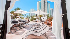 A rooftop terrace with sun loungers, umbrellas, and a view of tall buildings. - Magic Tropical Splash (Finestrat)