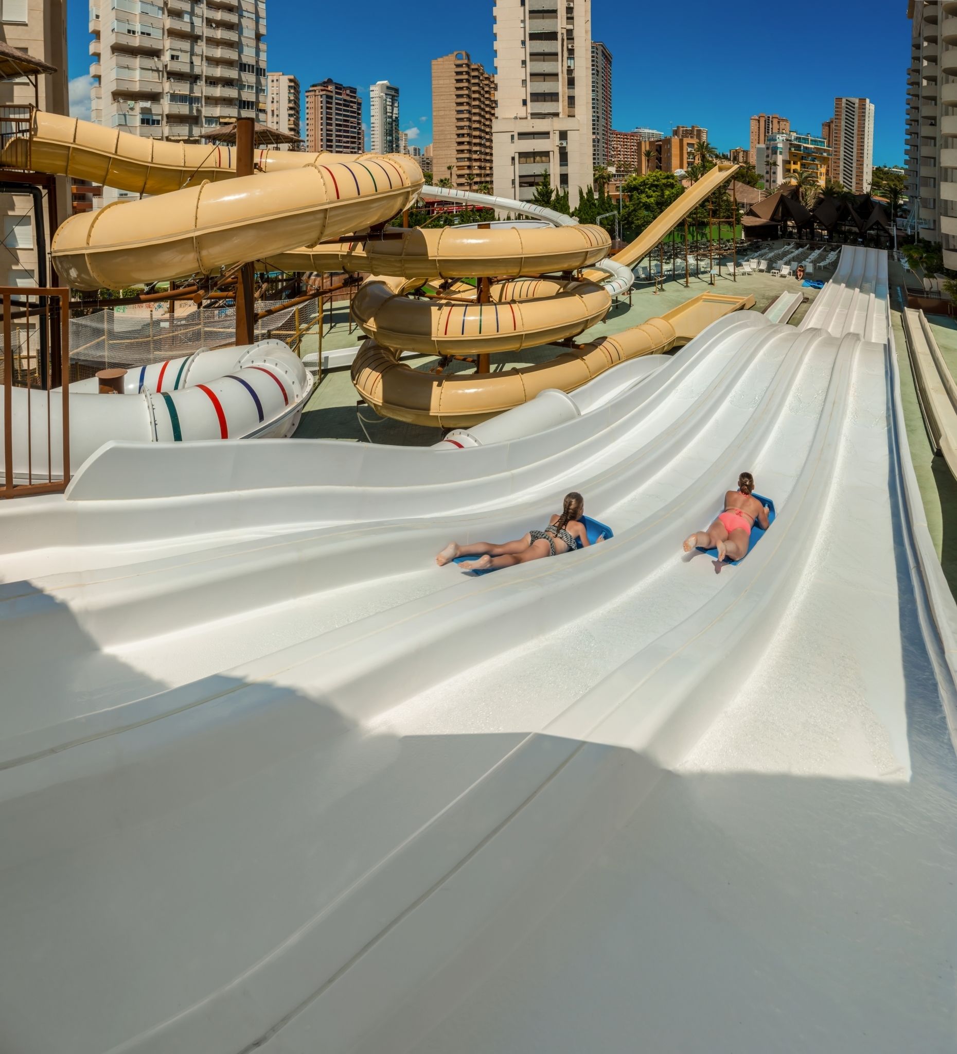 A water park with multiple water slides and a cityscape in the background.