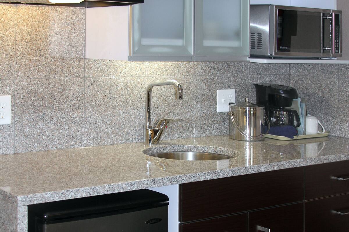 A kitchen with granite countertops, stainless steel appliances, and dark wooden cabinets.