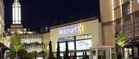 A Walmart store with a large illuminated sign, surrounded by other buildings and trees.