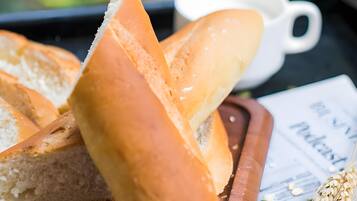 A wooden board with slices of bread, a white cup, and scattered grains.