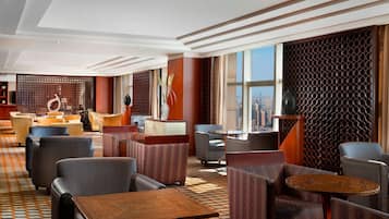 A modern hotel lobby with a patterned floor, seating areas, and large windows offering a city view.