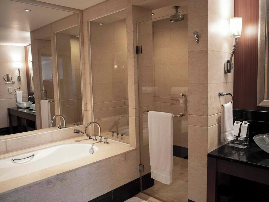 A modern bathroom with a large bathtub, a separate sink, and a glass shower enclosure.