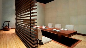 Una sala de reuniones moderna con una mesa larga, sillas y una estructura decorativa de listones de madera.