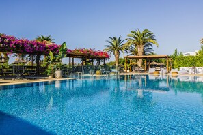 Una piscina con sillas de descanso y una pérgola cubierta de flores.
