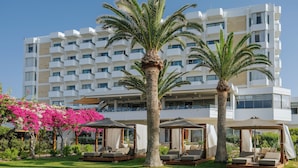 A modern hotel with multiple balconies, outdoor seating areas, and lush greenery.