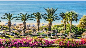 A beach resort with palm trees, sun umbrellas, and a view of the sea. - Alion Beach Hotel (Ayia Napa)
