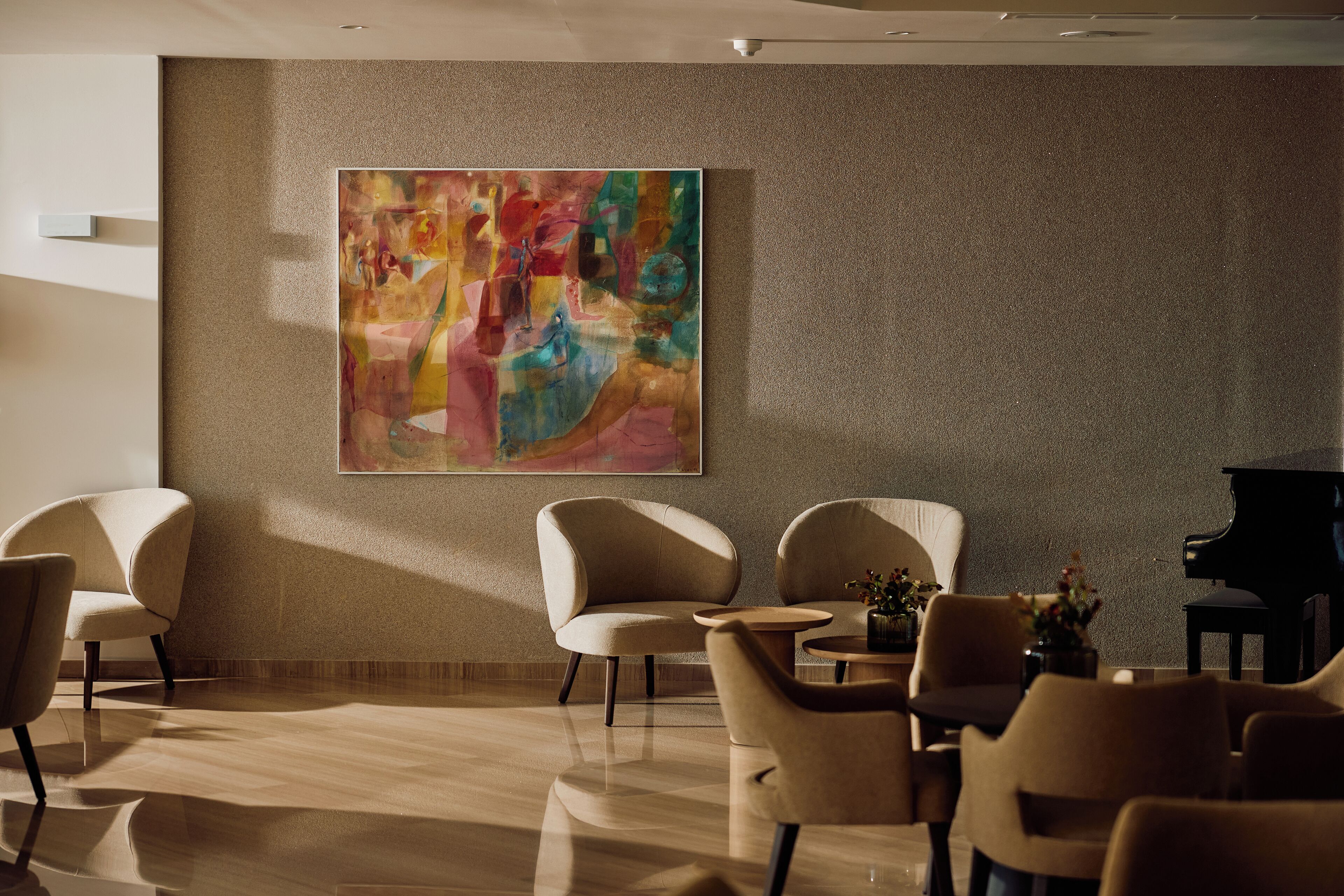 Een modern interieur met een groot abstract schilderij, comfortabele zithoek en een vleugelpiano.