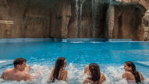 A pool with a waterfall feature and tiled steps leading into the water. - Magic Aqua Rock Gardens (Benidorm)