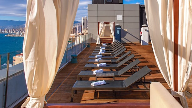 A sun deck with lounge chairs and a view of the city and sea. - Magic Aqua Rock Gardens (Benidorm)