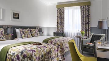 Habitación de hotel con dos camas, un escritorio, una silla y una lámpara.