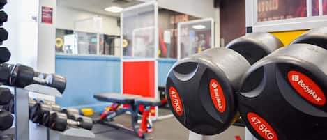 A gym with weightlifting equipment, including dumbbells and a bench.