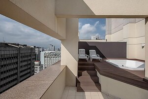 Una terrazza sul tetto con vasca idromassaggio, due poltrone relax e vista sulla città.
