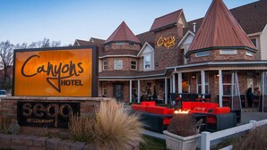 A hotel with a prominent sign, a patio with red seating, and a brick exterior. - Canyons Boutique Hotel, a Canyons Collection Property (Kanab)