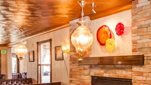 A restaurant with a brick fireplace, wooden tables, and orange chairs. - Canyons Boutique Hotel, a Canyons Collection Property (Kanab)