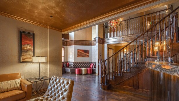 A spacious living area with a leather armchair, a sofa, and a staircase with a wooden railing. - Canyons Boutique Hotel, a Canyons Collection Property (Kanab)