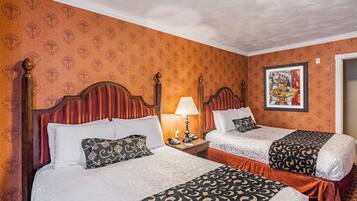 A hotel room with two beds, a nightstand with a lamp, a framed picture on the wall, and patterned wallpaper.