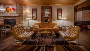 A cozy living room with a leather sofa, two armchairs, a coffee table, and a fireplace. - Canyons Boutique Hotel, a Canyons Collection Property (Kanab)