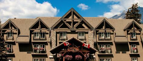 A multi-story hotel with a prominent entrance featuring a wooden archway and a sign.