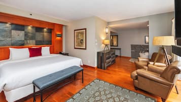 A hotel room with a large bed, a bench, a sofa, and a fireplace.