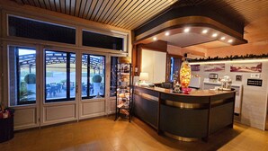 A hotel reception area with a large window, a reception desk, and a wall with framed pictures. - Ai Tigli (Langhirano)
