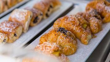 Eine Auswahl an Gebäck, darunter Croissants und Muffins, präsentiert auf einem Metallgestell.
