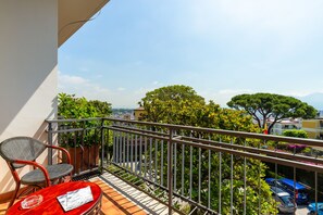 Enjoy the serene view from this balcony with a lush landscape and distant buildings.