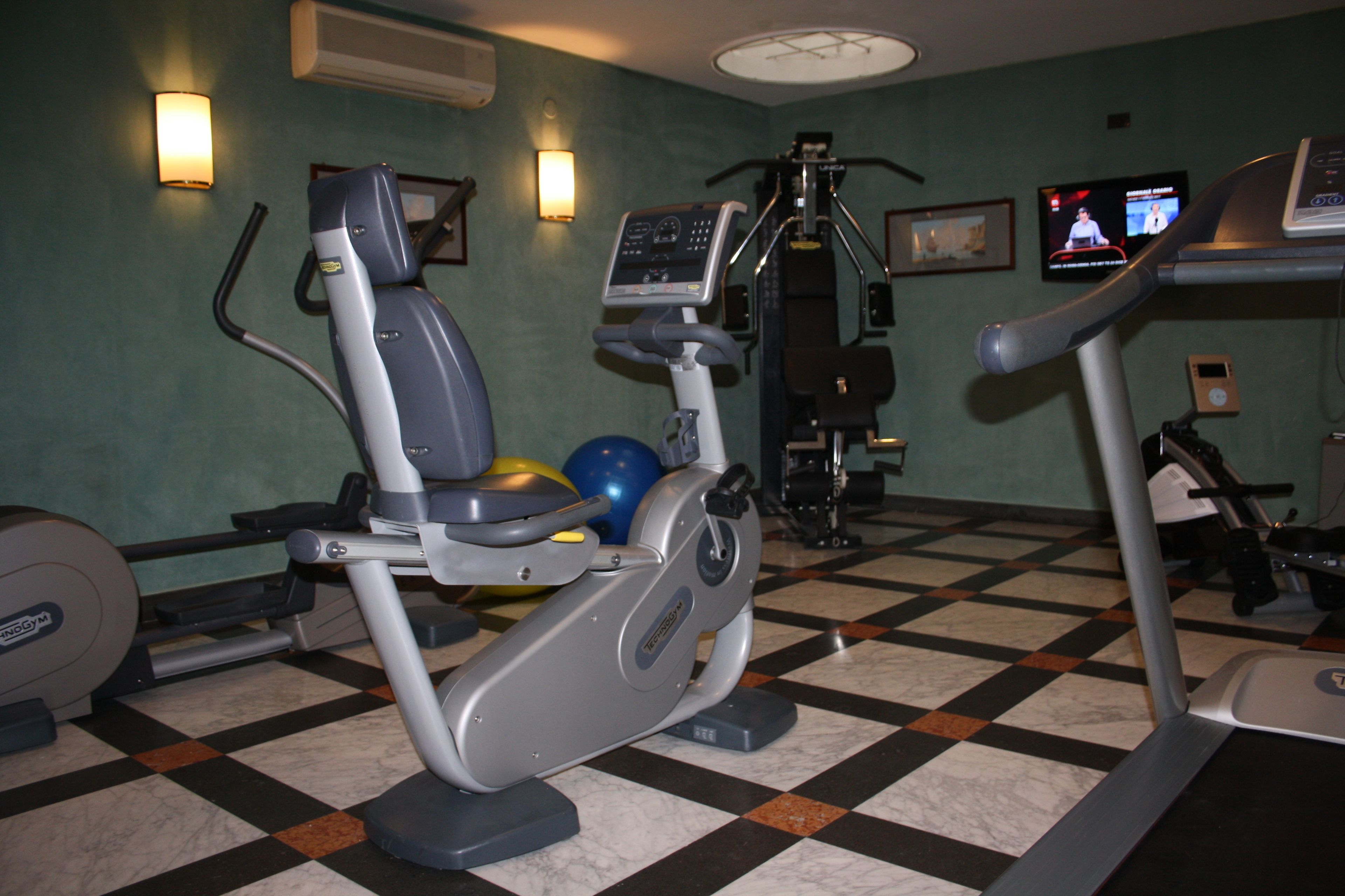 Une salle de sport équipée de matériel d’exercice, notamment un vélo d’appartement, un appareil elliptique et un tapis de course.