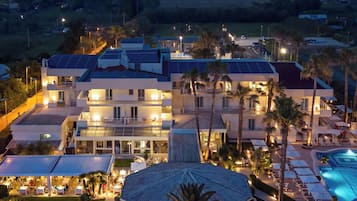 A multi-story hotel with a pool, outdoor seating, and solar panels.