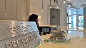 A reception desk at the Olympichotel Resort with a glass display case and a bell. - Hotel Olimpico (Pontecagnano Faiano)