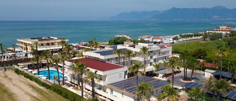 A coastal hotel with multiple buildings, a swimming pool, and solar panels.