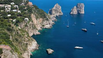A coastal area with rocky cliffs, clear blue water, and several boats.