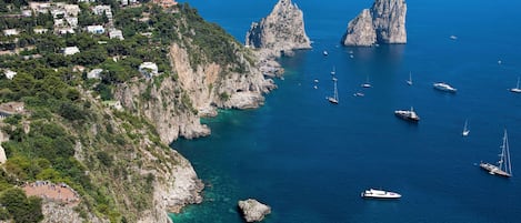 A coastal area with rocky cliffs, clear blue water, and several boats.