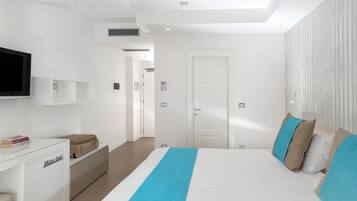 A modern hotel room with a large bed, a flat-screen TV, a desk, and a wardrobe.