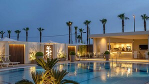 A pool area with lounge chairs, a bar, and palm trees. - Hotel Olimpico (Pontecagnano Faiano)